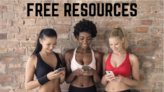 three young women smiling and looking at thier iphones. the are waering black, white and red sleeveless tank tops. they are working out at the gym and just finished their yoga exercise. they just downloaded some free resources about how to cope with stress and anxiety.